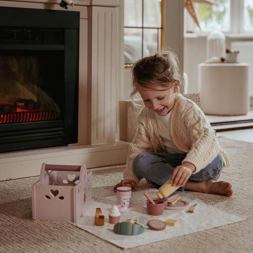 kind spielt mit little dutch picknickkorb vor dem Kamin