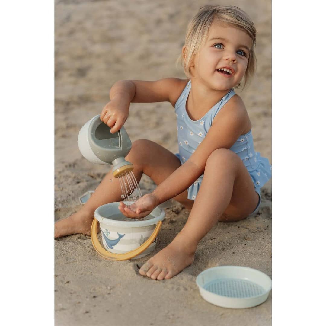 kind spielt mit sandspielzeug am strand